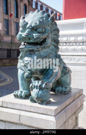 Chinese Guardian Lion, Chinatown, Liverpool alongside the chinese arch or chinese gate in Chinatown Liverpool. Stock Photo
