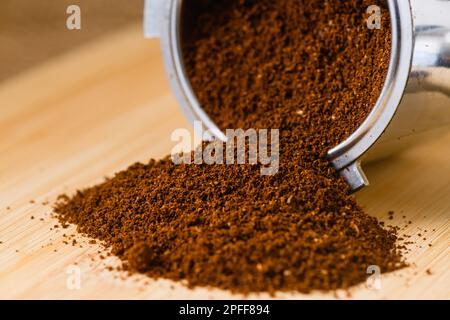 Close up macro texture of ground espresso coffee in metal holder on wooden table. Stock Photo