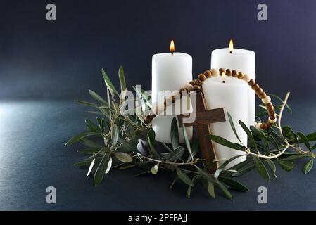 Easter religious background with three burning candles christian cross and olive branches around. Front view. Stock Photo