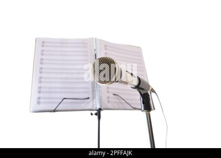 Microphone and music stand with folder with sheet music behind isolated on white background. Front view. Stock Photo