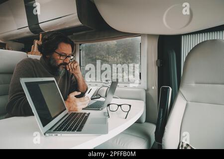 Freedom job alternative office man at work inside camper van in travel lifestyle nomad vacation modern smart working. Online communication. One male p Stock Photo