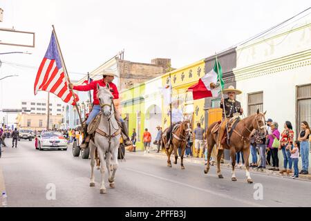 Matamoros, Tamaulipas, Mexico - February 25, 2023: Fiestas Mexicanas Parade, Men riding horses carrying the Mexican and American Flag Stock Photo