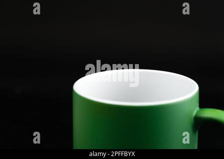 Empty green ceramic mug on a black background, macro photography Stock Photo