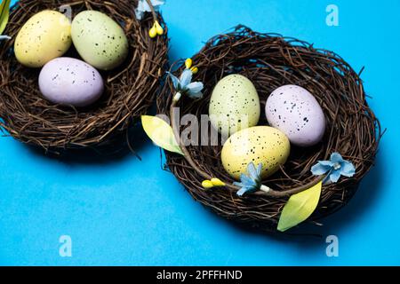 Easter eggs in wicker nest baskets on a blue background Stock Photo
