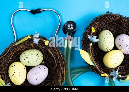 Easter Medicine. Two nests with painted eggs and a stethoscope on a blue background. Stock Photo
