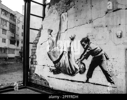 Black and white. Mural by Banksy in Borodyanka on a ruined building, The image of a boy defeating an adult, similar to the Russian president, man dres Stock Photo