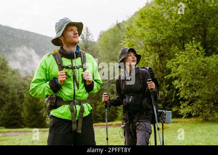 Young white people wearing trekking equipment hiking in mountain forest Stock Photo