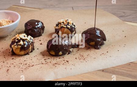 Delicious profiteroles with chocolate, concept of homemade pastry, chocolate and hazelnut presentation of profiteroles, close-up. Stock Photo