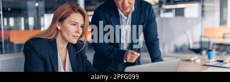 Two multiethnic coworkers working together analyzing the charts in office Stock Photo