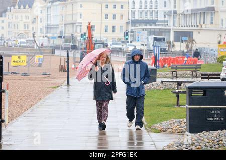 Hastings, East Sussex, UK. 17 Mar, 2023. UK Weather: Heavy rain expected throughout the day at the seaside town of Hastings in East Sussex. A couple walking along the seaside promenade holding an umbrella. Photographer: Paul Lawrenson, Photo Credit: PAL News /Alamy Live News Stock Photo