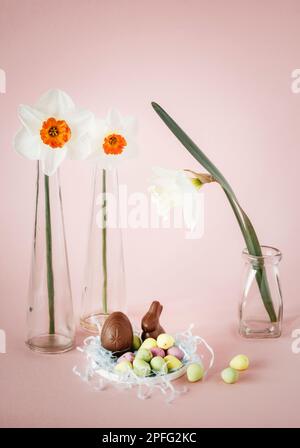Easter still life with daffodils in glass vases, easter eggs and mini chocolate bunny Stock Photo