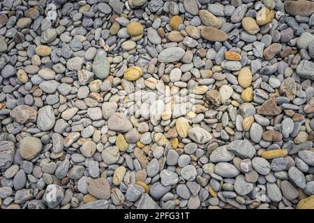 Set of rounded stones of different sizes and in gray tones on a beach. Stock Photo