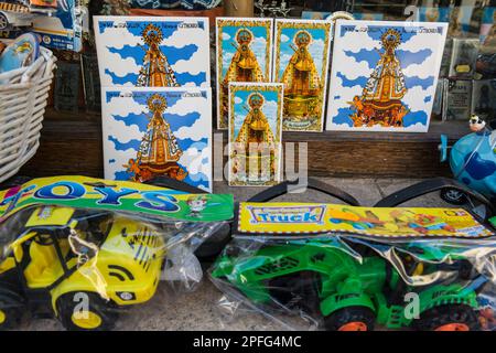 Religious souvenirs in a shop window of  'Our Lady of Guadalupe' among toys in a souvenir shop. Guadalupe, Caceres province, Extremadura, Spain. Stock Photo