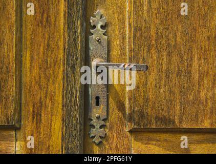 Old vintage door handle on a wooden door - covered with rust and time passing Stock Photo