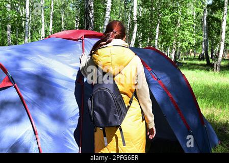 A girl sets up a camping tent during her stay in nature Stock Photo