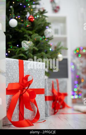 Silver gifts with red ribbons under Christmas tree. Stock Photo