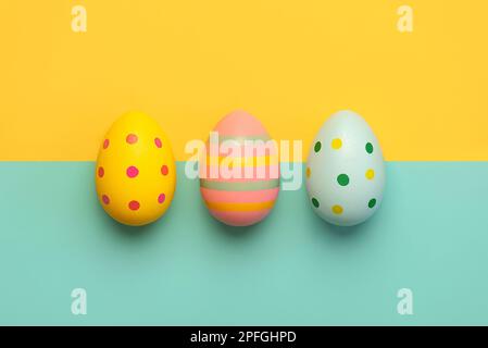 Happy Easter. Close-up of three easter eggs over blue and yellow background Stock Photo