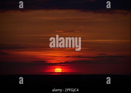 I can see the sun setting in a cloudy sky Stock Photo