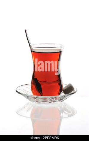 classic turkish tea glass on a glass plate and with sugar cubes on white background Stock Photo