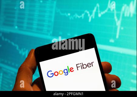 In this photo illustration, the American fast Internet service provider by Google, Google Fiber, logo is seen displayed on a smartphone with an economic stock exchange index graph in the background. Stock Photo