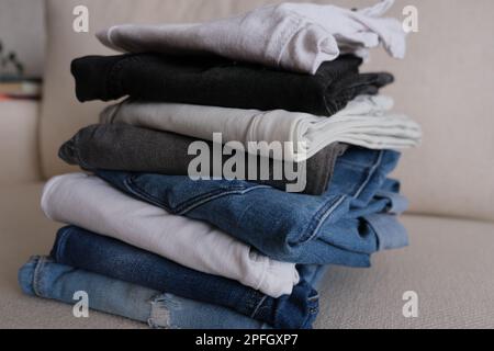 Denim pants, folded and stacked denim pants on a white sofa, denim fabric concept idea photo. Stock Photo