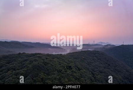 Pink predawn color in sky over green hilly landscape with morning mist Stock Photo