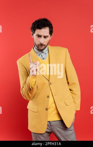displeased man in yellow jacket pointing with finger while warning isolated on coral red,stock image Stock Photo