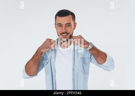 Fashionable young man standing indoors against white background Stock Photo