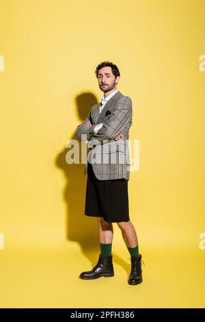Full length of trendy model in jacket and shorts crossing arms on yellow background,stock image Stock Photo