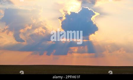 sunset, the rays of which break through the clouds creating a silhouette and contour of the clouds Stock Photo