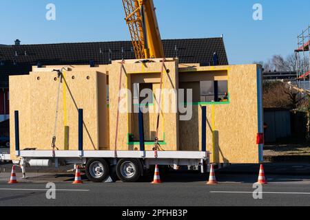 Ready for unloading panels of a wooden prefabricated house. Crane boom at the back. Car trailer. Stock Photo