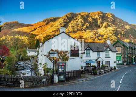 Coniston village in the Lake district of Cumbria. Evening autumn. The Black Bull Inn beside the Church Beck stream. Stock Photo