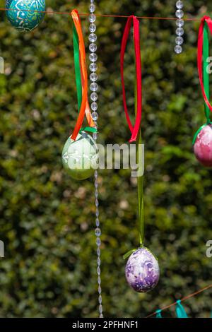 Painted eggs hang from the branches of the Easter tree. The focus is on a yellow egg painted by children by hand. High quality photo Stock Photo