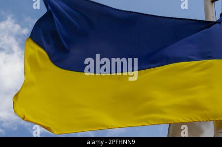 Ukrainian flag waving in wind and sunlight. Flag of Ukraine on blue sky background. National symbol of freedom and independence. Stock Photo