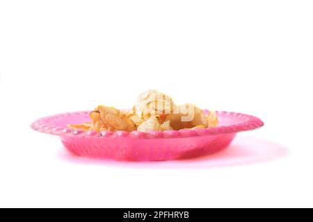 Crispy fried Potato chips on pink plastic plate isolated on white background. Selective focus. Stock Photo