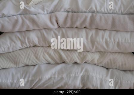 Stacked white pillows are on a furniture as a background photo. Many pillows are in a row. Stock Photo