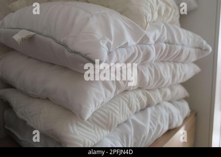 Stacked white pillows are on a furniture as a background photo. Many pillows are in a row. Stock Photo
