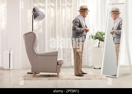 Full length shot of a senior gentleman getting dressed in front of a mirror at home Stock Photo