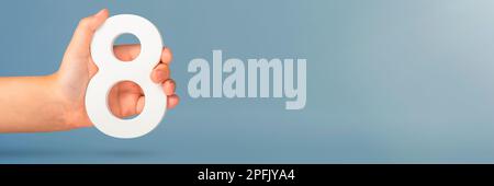 Eight in hand. A hand holds a white number 8 on a blue background. Concept with number eight. Birthday 8 years, percentage, eighth grade or day Stock Photo
