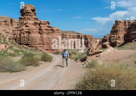 Man walking on the road in Sharyn Canyon National Park and Valley of Castles, Tien Shan Mountains, Kazakhstan Stock Photo