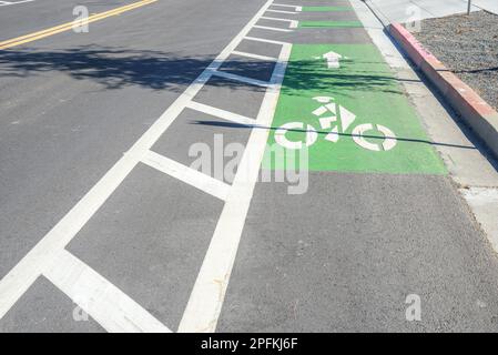 Bicycle lane marked in green along a road in a business park on an autumn sunny day Stock Photo