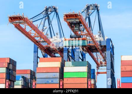 Huge port cranes loading a cargo ship with containers on a sunny summer day Stock Photo