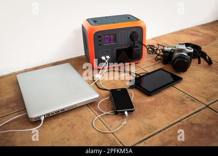 Portable power station solar electricity generator with laptop, phone, tablet and camera charging.  Stock Photo