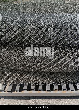 A metal mesh chain-link twisted in rolls lies on a metal base Stock Photo