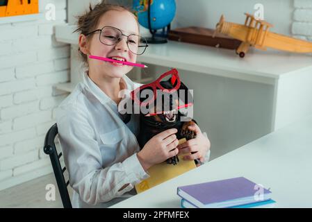 Back to school idea concept with funny dog holding pencil. Smart and clever dog with pencil and glasses. Stock Photo