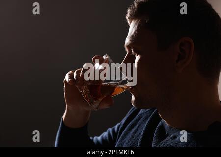 Addicted man drinking alcohol on dark background, closeup Stock Photo