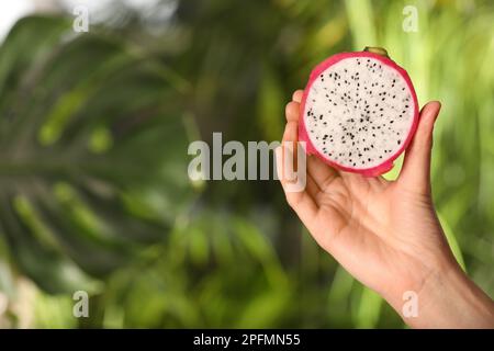 Woman holding fresh cut dragon fruit (pitahaya) on blurred background, closeup. Space for text Stock Photo