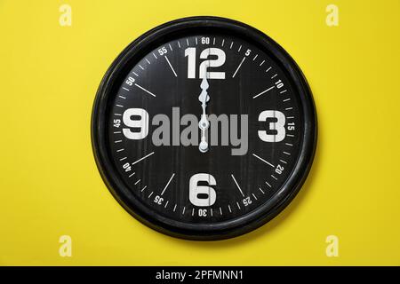 Modern black clock on yellow background, top view Stock Photo