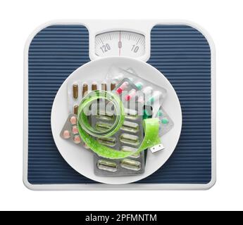 Scales with plate of pills and measuring tape on white background, top view Stock Photo
