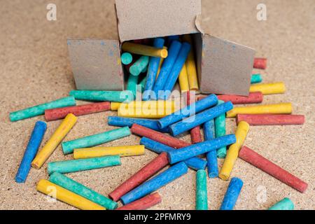 Colorful chalks scattered out of a box on a desk Stock Photo